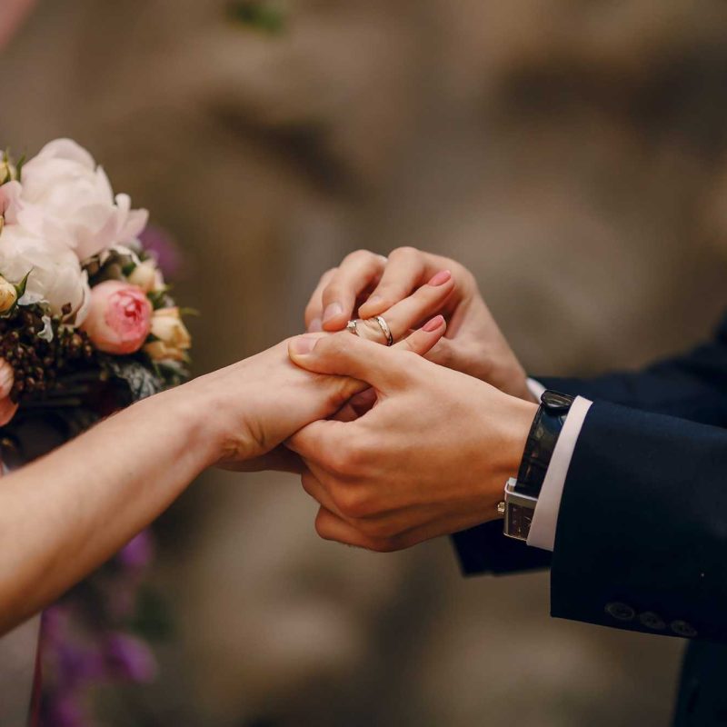 groom putting ring bride s finger